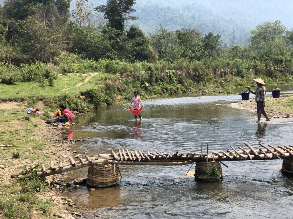Habitants au bord d’une rivière dans un paysage montagneux du Laos.