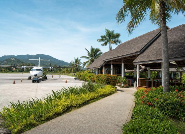 Koh Samui Airport, thatched-roof pavilions and plane on the tarmac.